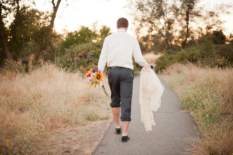 groom trekking up the hill in wet clothes from photo session
