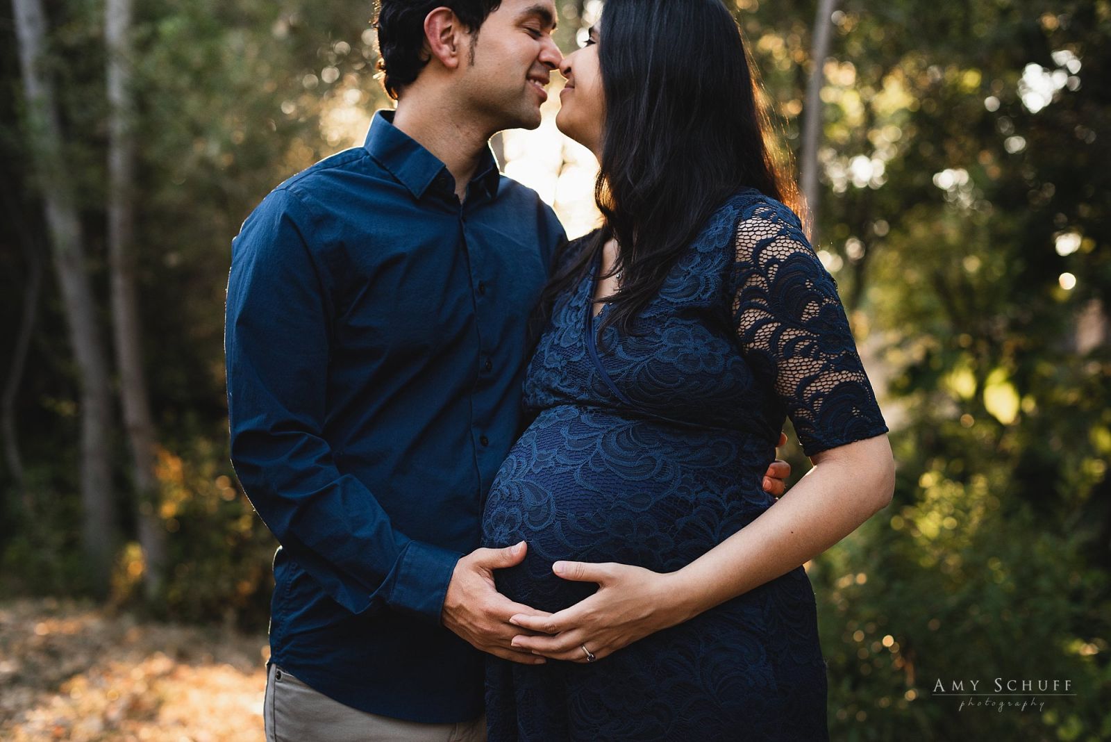 Pregnant mom and dad kissing in the sunlight