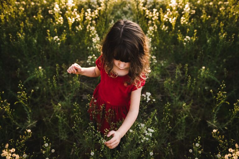 A little girl in red in field of flowers sun beaming down on her sacramento ca photography